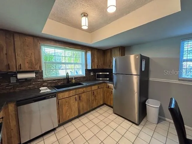 a kitchen with stainless steel appliances granite countertop a refrigerator a sink a stove a washer dryer and a cabinets