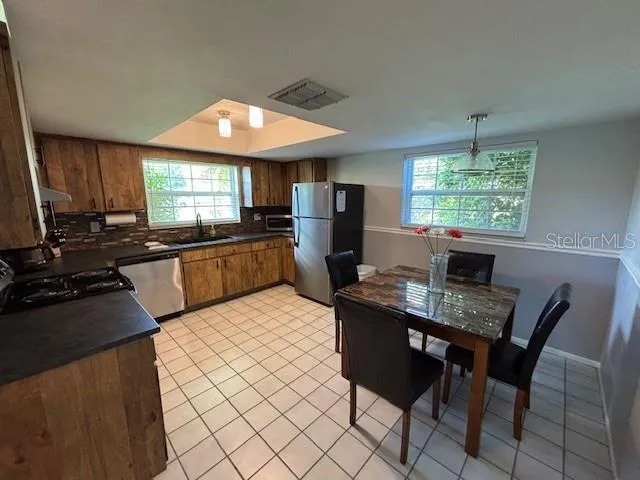 a kitchen with stainless steel appliances granite countertop a stove a sink dishwasher a dining table and chairs