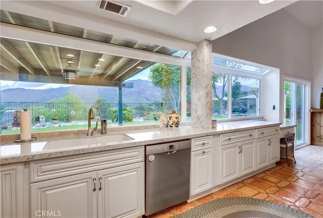 a kitchen with stainless steel appliances granite countertop a sink window and cabinets