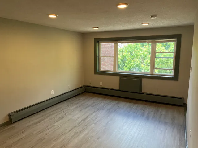 an empty room with wooden floor and windows