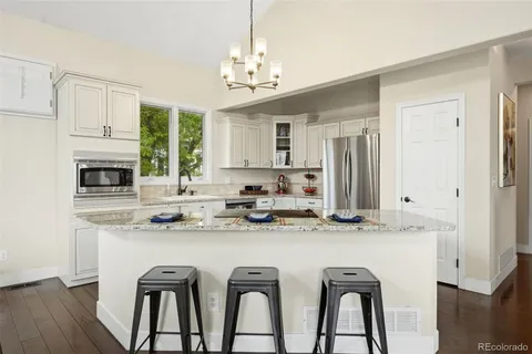 a kitchen with stainless steel appliances granite countertop a dining table and chairs
