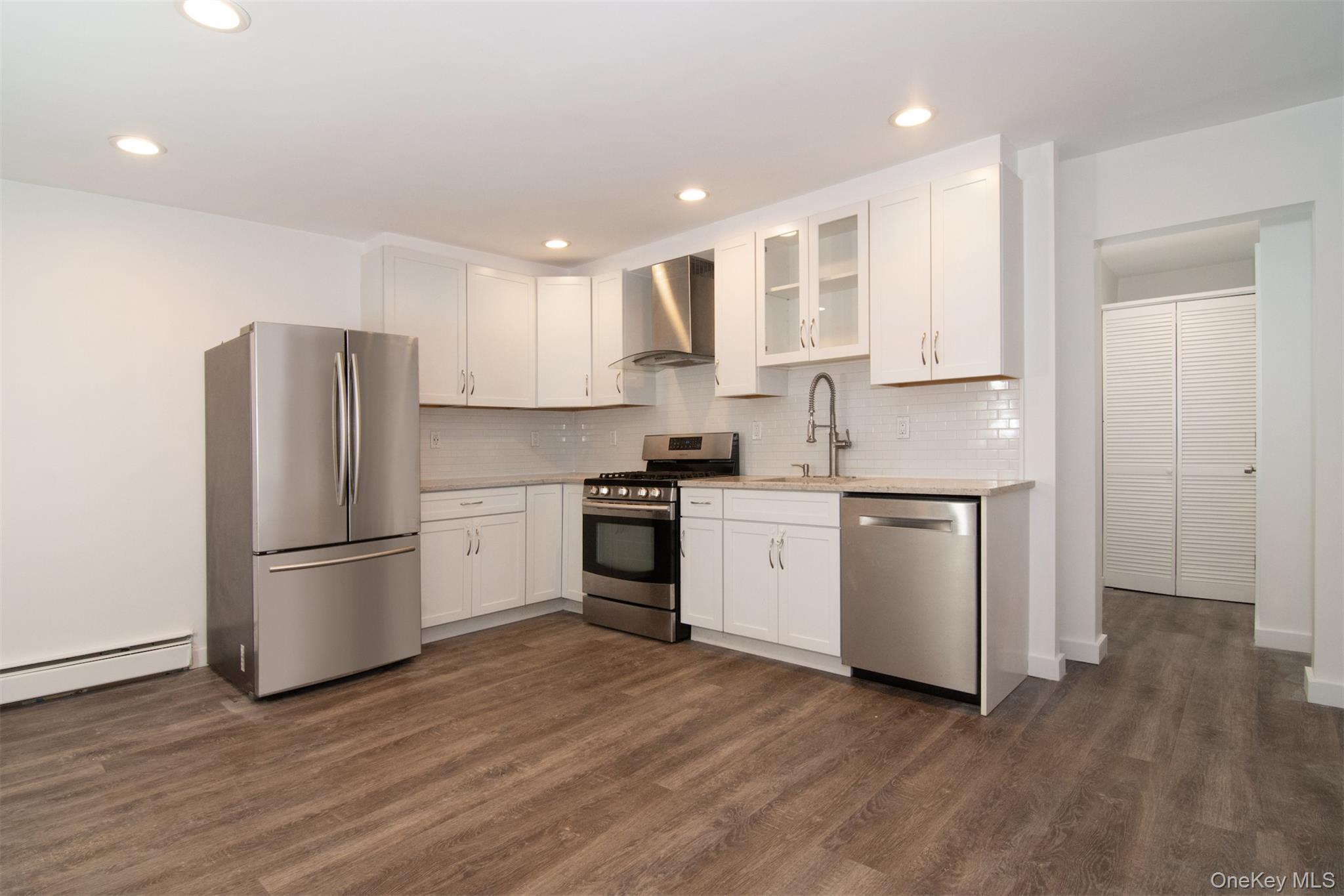 44 Ridge Street, Unit 1 Hastings-on-Hudson, NY 10706 - Photo 3 of 16 Kitchen with sink, appliances with stainless steel finishes, white cabinets, wall chimney exhaust hood, and dark wood-type flooring