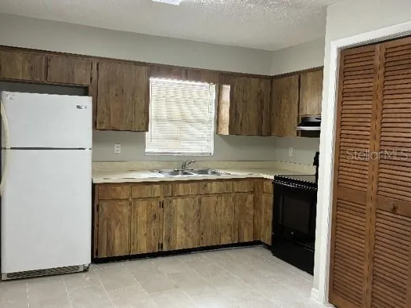 a kitchen with granite countertop a refrigerator and a sink