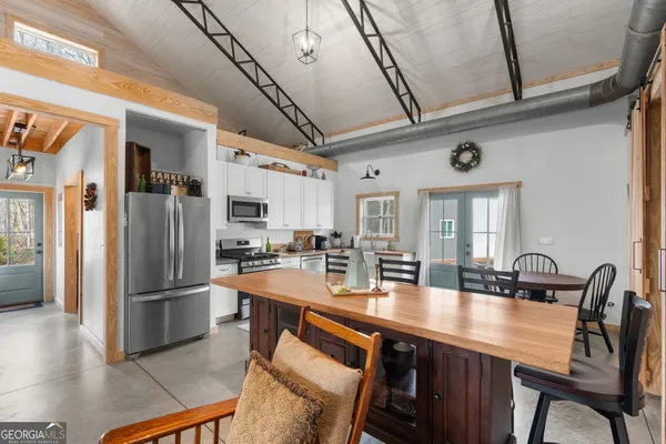 a kitchen with stainless steel appliances granite countertop a stove top oven a sink a dining table and chairs with wooden floor