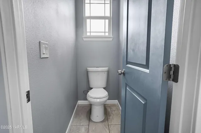 a white toilet sitting in a bathroom next to a window