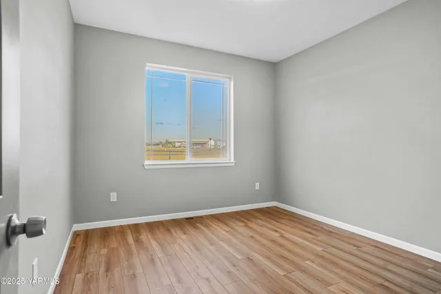 an empty room with a hardwood and a window