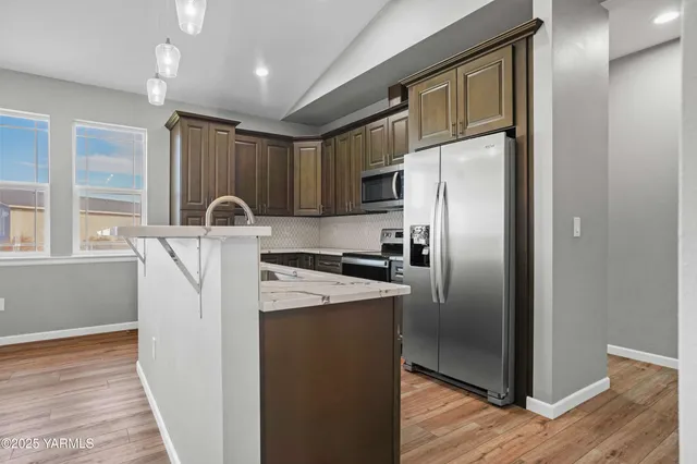 a kitchen with kitchen island stainless steel appliances a refrigerator sink and stove