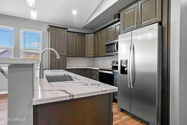 a kitchen with stainless steel appliances granite countertop a refrigerator a stove a sink and a cabinets