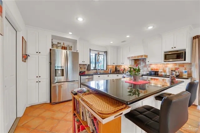 a kitchen with stainless steel appliances granite countertop a refrigerator a stove and a sink