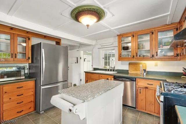 a kitchen with granite countertop stainless steel appliances a stove refrigerator and cabinets