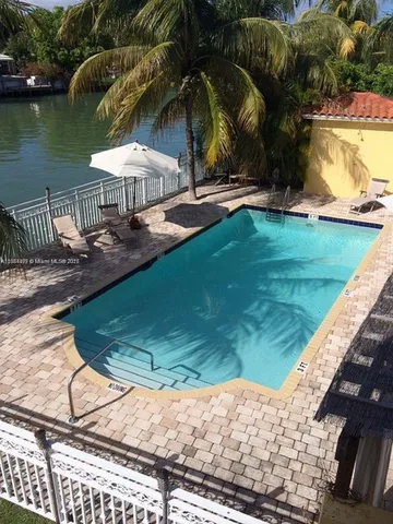 a view of swimming pool with lawn chairs and plants