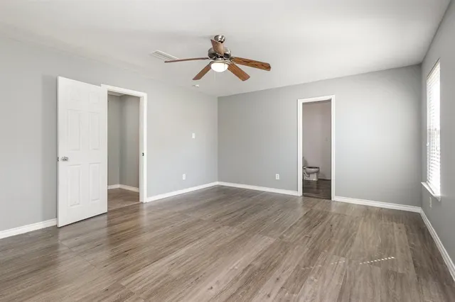 an empty room with wooden floor chandelier fan and windows