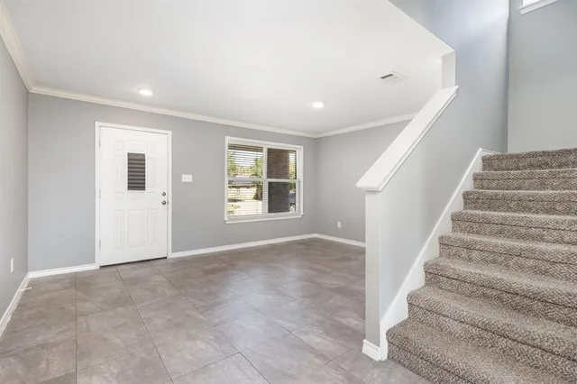 a view of an empty room with wooden floor and windows