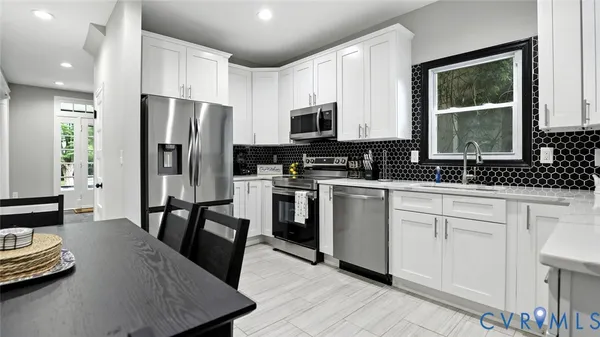 a kitchen with a stove a sink a microwave a dining table and chairs