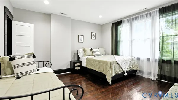a bedroom with two beds and wooden floor