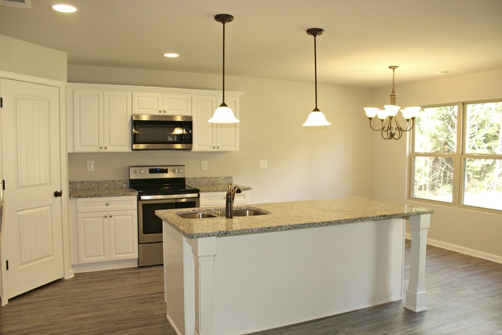 965 Weldon Road Forsyth, GA 31029 - Photo 4 of 11 a kitchen with stainless steel appliances granite countertop a sink a microwave a stove and a wooden floor