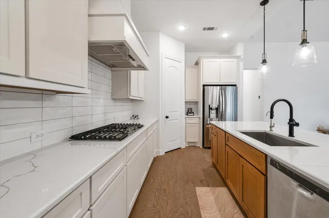 a kitchen with kitchen island stainless steel appliances a sink a stove and a refrigerator