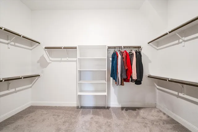a view of walk in closet with clothes and shoes