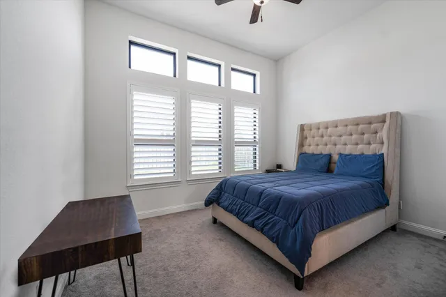 a bedroom with a bed a chair and a large window