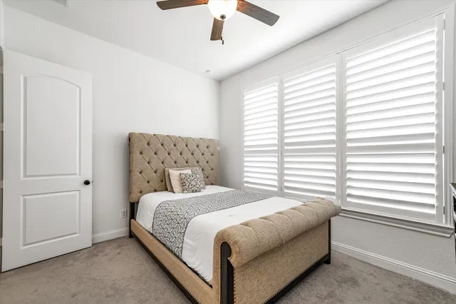 a bedroom with a large bed and a chandelier fan