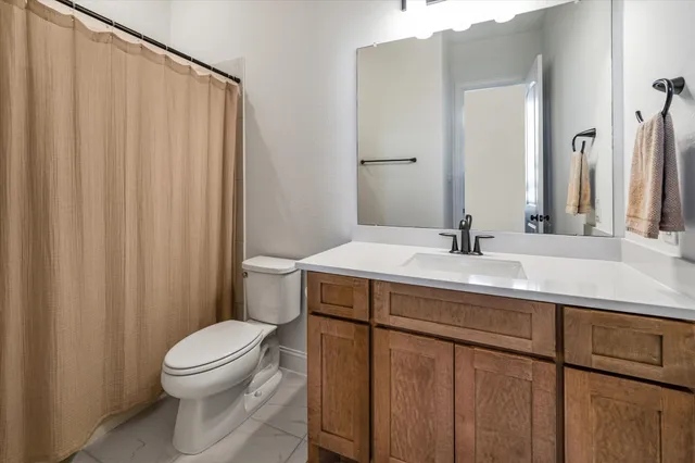 a bathroom with a sink a toilet a mirror and shower curtain