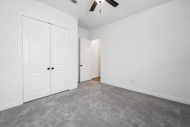 an empty room with closet and chandelier fan