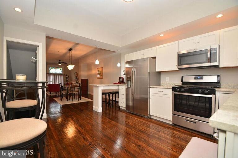3529 Wild Cherry Road Baltimore, MD 21244 - Photo 12 of 30 a kitchen with stainless steel appliances a dining table chairs stove microwave and cabinets
