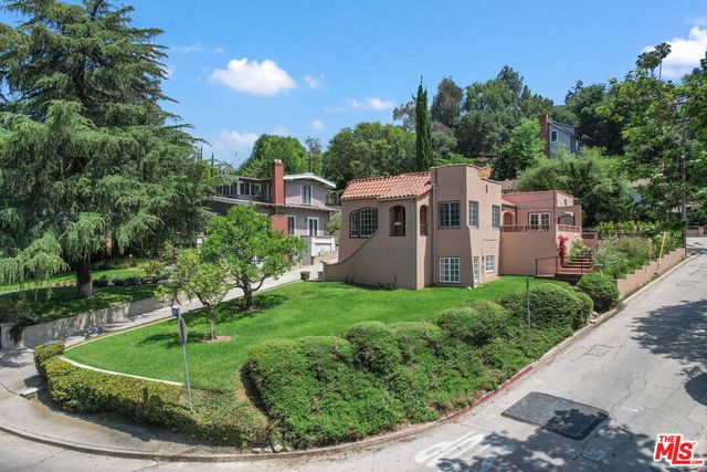 a view of a house with a yard and potted plants