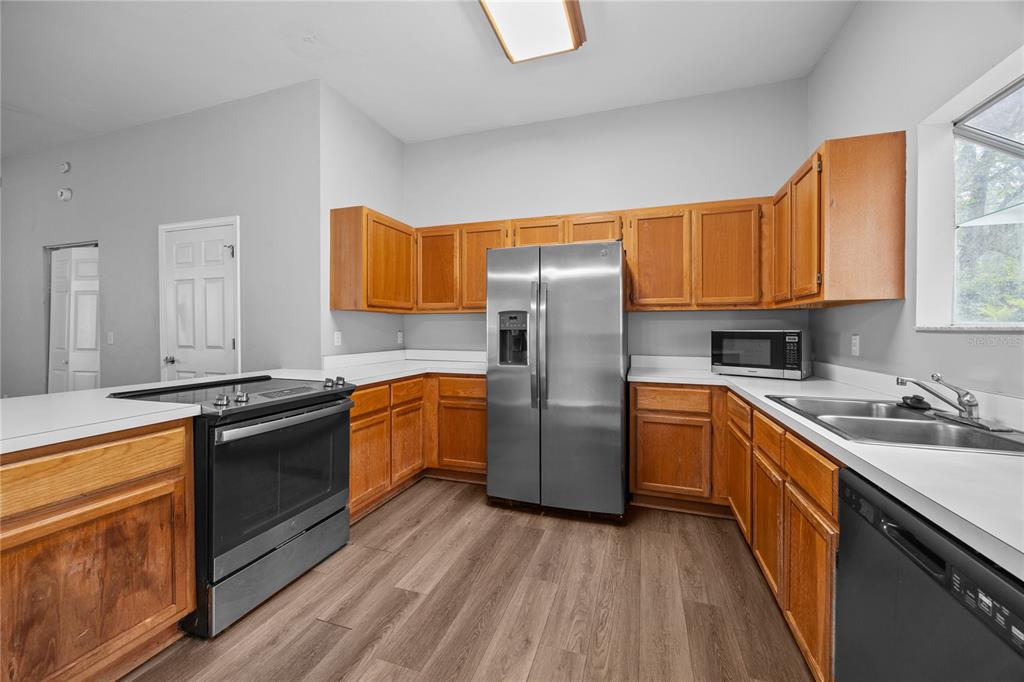 5291 Southwest 97 Way Gainesville, FL 32608 - Photo 12 of 24 a kitchen with stainless steel appliances granite countertop a refrigerator a sink dishwasher a stove and white countertops with wooden floor