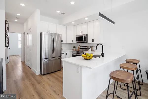 a kitchen with a refrigerator a stove a sink and a microwave with wooden floor