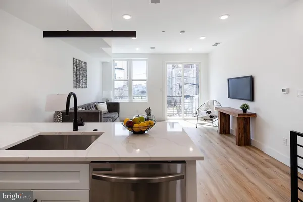 a kitchen with a sink appliances and wooden floor