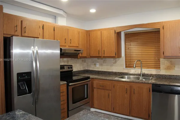 a kitchen with stainless steel appliances granite countertop a refrigerator and a sink