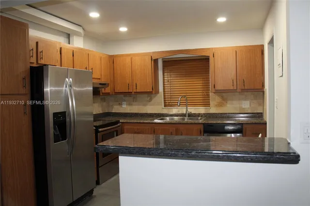 a kitchen with stainless steel appliances granite countertop a refrigerator a sink and a stove