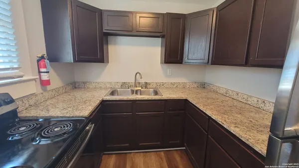 a kitchen with kitchen island granite countertop wooden cabinets and a sink