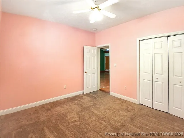 an empty room with closet and a chandelier fan