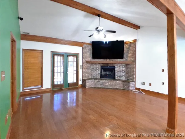 a view of a livingroom with a fireplace a ceiling fan and windows