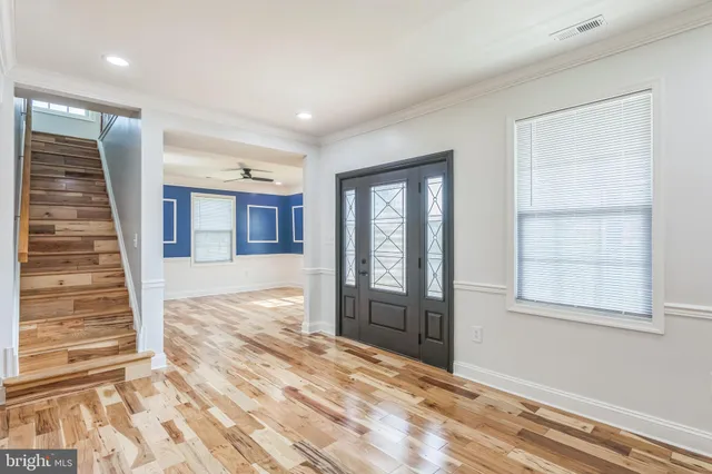 a view of an empty room with wooden floor and windows