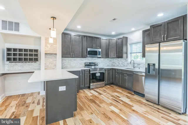 a open kitchen with stainless steel appliances granite countertop a stove a sink dishwasher a refrigerator and a oven with wooden floor