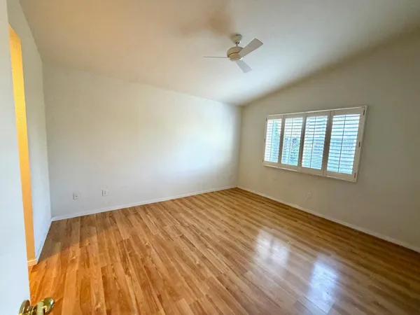 a view of empty room with wooden floor and fan