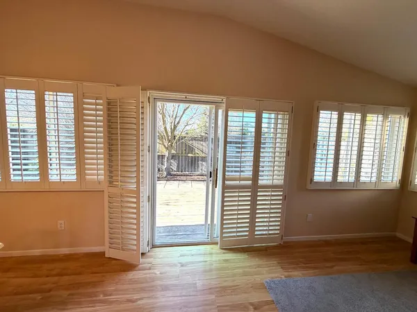 an empty room with wooden floor and windows