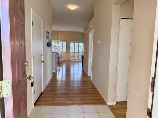 a hallway with wooden floor table and chairs