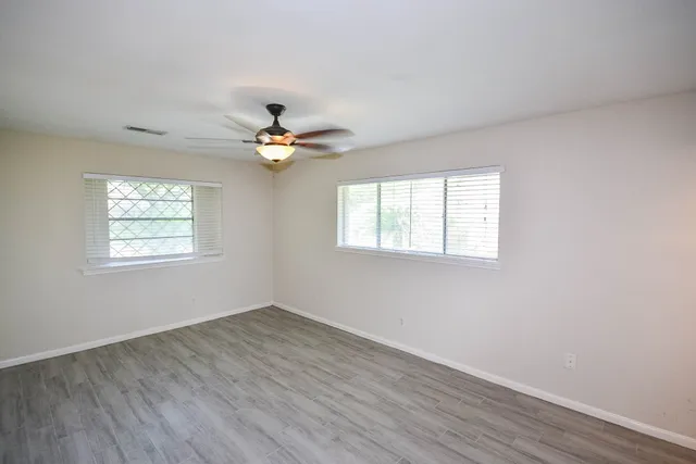 a view of an empty room with wooden floor and a window