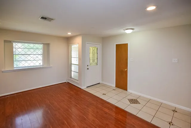 an empty room with wooden floor and windows
