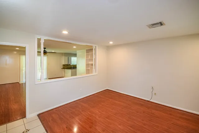 a view of empty room with wooden floor and fan