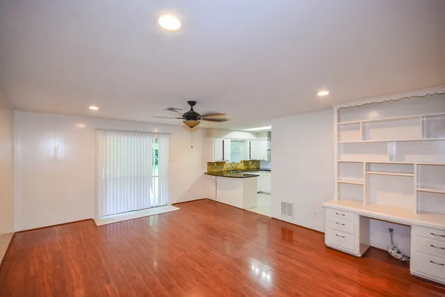 a big room with chandelier fan and windows