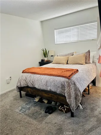 a bedroom with a bed a table and potted plant