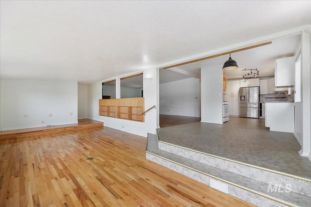 7141 West Hill Road Boise, ID 83714 - Photo 8 of 28 Spacious living area featuring light wood-finish flooring, multiple large windows, and white walls