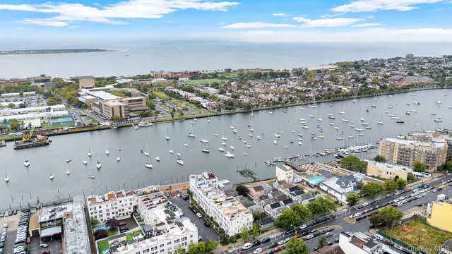 an aerial view of a city with lots of residential buildings ocean and mountain view in back