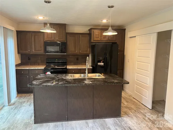 a kitchen with kitchen island granite countertop a sink a counter top space and appliances