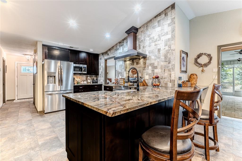 8480 Colma Street Spring Hill, FL 34606 - Photo 25 of 70 a kitchen with stainless steel appliances granite countertop a table chairs and a refrigerator